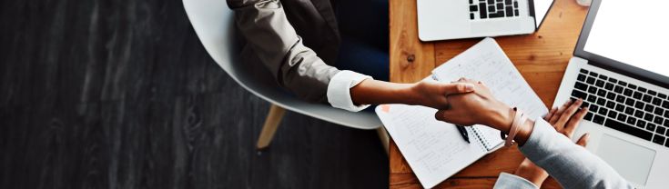 Two businesswomen shaking hands in an office