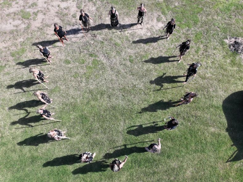 drone birds eye image of a circle of people standing on green grass