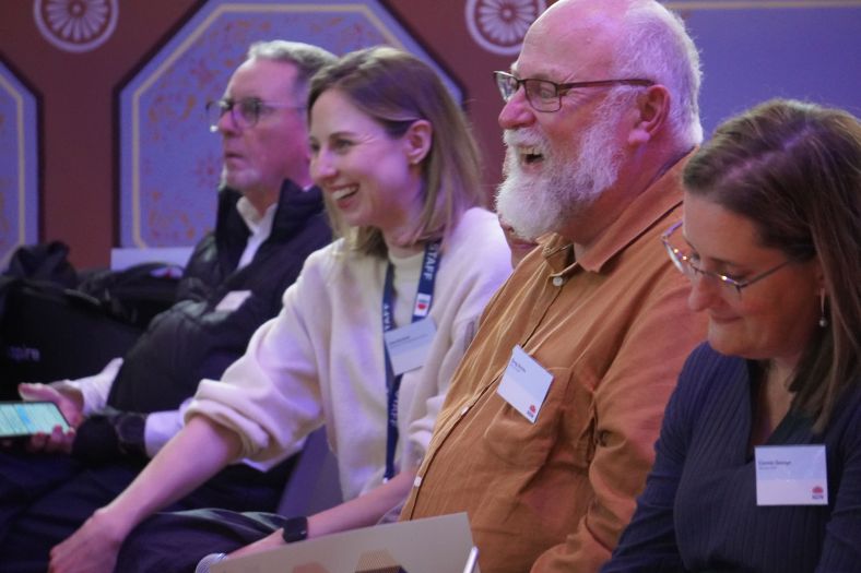 Four people laughing in the audience of the NSW Digital Inclusion Strategy launch